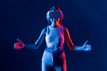 Smart Female standing surrounded by neon light wear VR headset connecting metaverse, futuristic...