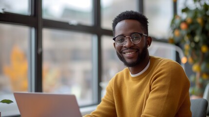 Smiling African American man working from home with a laptop in a bright room, Concept of remote work, digital nomad lifestyle, and modern workplace flexibility