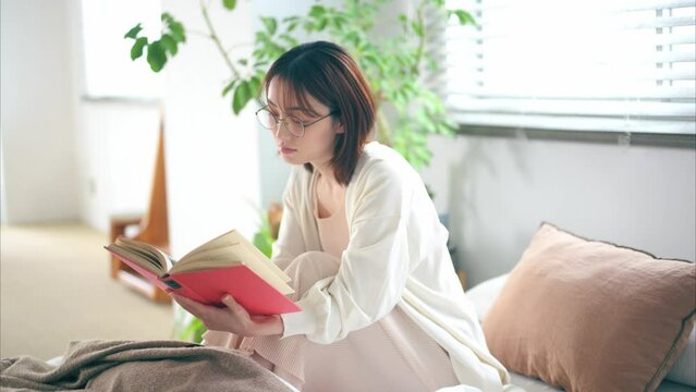 ベッドで本を読む20代女性