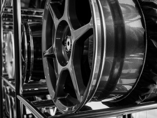 Close-up alloy wheels rim decoration on metal shelf in tire store background. Black and white...