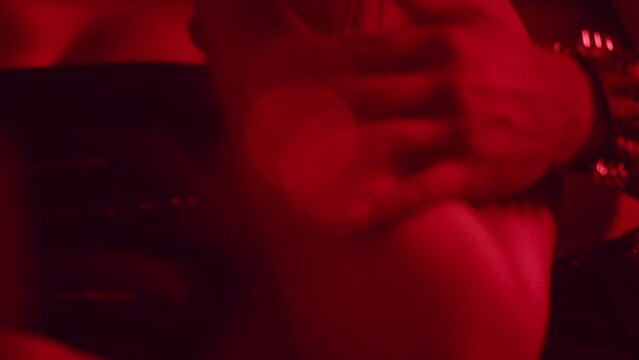 Man rubbing woman's arm in red lit room