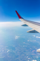 View from the airplane window at a beautiful cloudy sky and the airplane wing