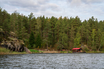 Wooden bathhouse and boat pier on the shore of Lake Ladoga near the village of Lumivaara on a sunny autumn morning, Ladoga Skerries, Lahdenpohya, Republic of Karelia, Russia