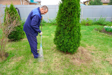 A man works in the garden in early spring, cleaning the lawn