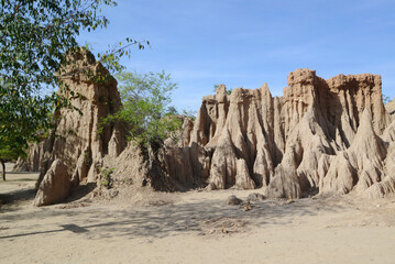 Fototapeta premium Sao Din Na Noi topography is formed from weathering and erosionare sedimentary patches that look like steep cliffs, bars, cones, recesses, and pointed peaks, emerging from the ground on an open field.