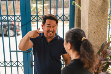 An Asian man mocks his wife's mannerisms during a heated debate near the gate of their home.