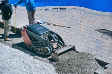 Landscape workers working on residential backyard landscaping site to measure and build the...