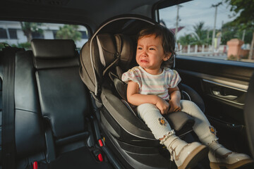 crying toddler girl sitting in car seat, safety baby chair travelling