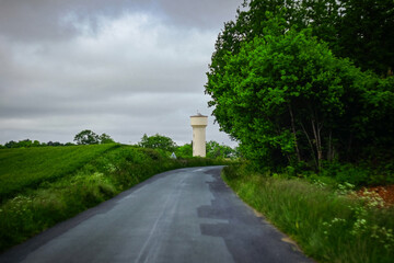 Curved country road with water tower in the distance, in Charente Maritime, France