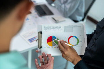 A man is pointing at a pie chart on a clipboard. The chart is divided into four sections, with the...