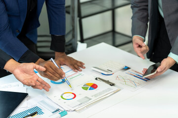 Three people are looking at a table with graphs and charts. They are discussing the data and making decisions based on the information