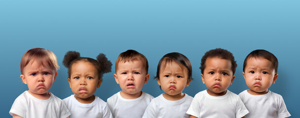 Six unhappy babies on blue background with copy space.