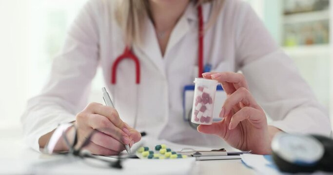 Therapist medicine doctor holds jar of pills and writes out prescription to patient