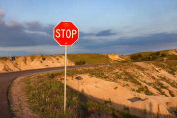 A stop sign on the edge of a cliff at Badlands National Park, at sunset time, South Dakota