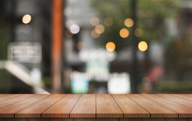 Empty wooden table top with lights bokeh on blur restaurant background.
