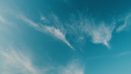 Floating fluffy clouds. Beautiful sunny blue sky with wispy smoky white cirrostratus.