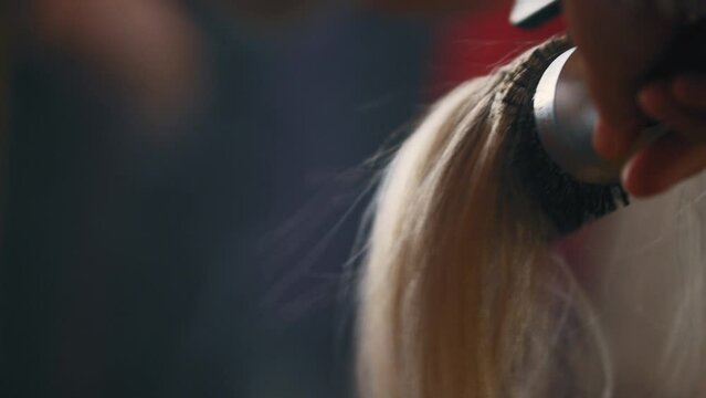 Hair stylist blow drying hair and styling it with a round brush