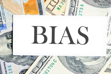 Concept of facts and biases. A word BIAS on a white business card lying on dollars