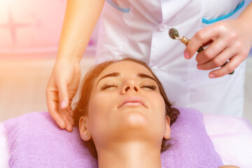 Facial massage. Side view european woman getting massage with jade face roller gouache in spa salon
