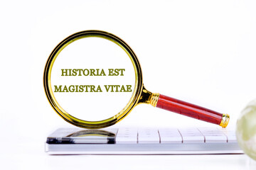 Historia est vitae magistra (History is the tutor of life) Latin phrase inscription was found using a magnifying glass on the calculator. Concept photo