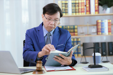 Lawyer sitting in his office On the table with a small hammer judge in court and the scales of...