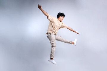 Full Length of Attractive Young Man Jumping and Dancing Isolated on White Background 
