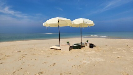 photo of crashing waves on the shoreline, umbrella and chairs on the beach