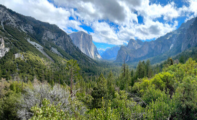 Fototapeta premium Panoramic View of El Capitan, Half Dome, and Bridalveil Fall at Yosemite National Park, California. Spring Season. Cloudy Skies. 