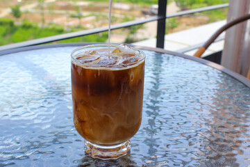 glass of iced coffee and milk pouring