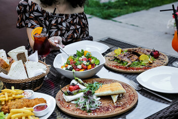 Woman Sitting at Table With Various Plates of Food