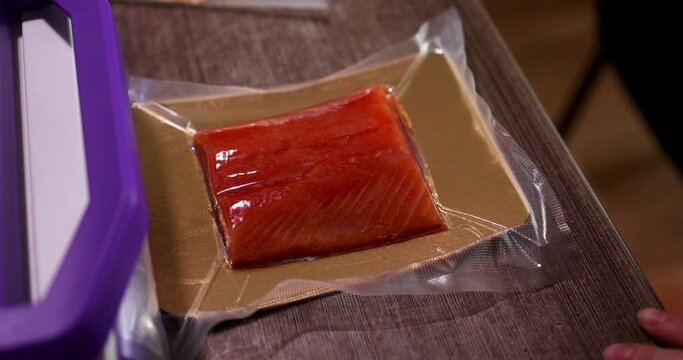 A piece of fish is wrapped in a film and placed on a table and vacuumized to preserve the quality and shelf life. High quality 4k footage
