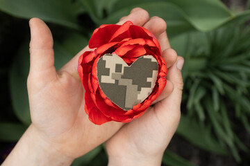  red flower and heart cut out of camouflage military fabric on child's palms. Stop war. With love...