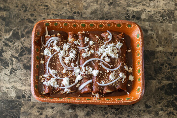 high view of plate with red mole enchiladas, enmoladas with cheese and onion. Mexican food