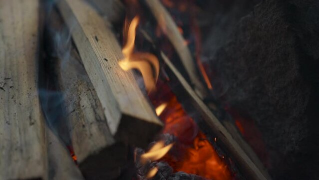Campfire in the forest. Beautiful wooden campfire on fire between rocks, with particles of fire and ash. Camping, 4k video, close-up