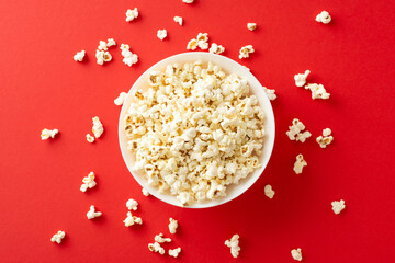 Home cinema experience with TV app. Top view of popcorn in bowl. Red background with space for text...