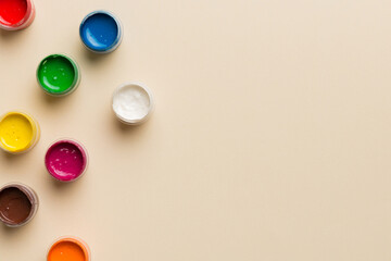 jars with gouache of different colors on Colored background. hobby painting. Top view with empty space. workplace for creativity. home teaching concept drawing