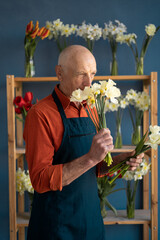 European elderly man florist inhales the smell of flowers.