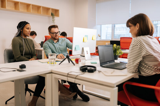 Modern corporate office open space with busy male and female staff employees using laptop computers sitting at work in big modern corporate office. Startup team working together at creative open space