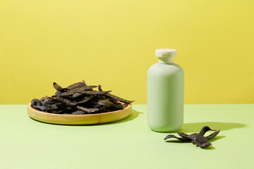 Unbranded bottle in pastel green color decorated with a wooden dish of black locust. Yellow...
