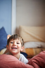 Child wakes up with a big smile in the bed of his room