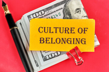 Culture of belonging symbol on a sticker lying on dollar bills on a red background, next to a...