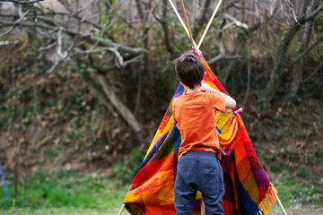 A child building a tepee in the backyard.