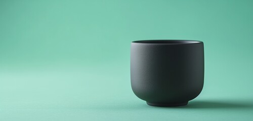 A cool, mint green background featuring a solitary, black ceramic cup, its matte finish and simple form representing the essence of minimalist lifestyle and design. 32k, full ultra hd, high resolution
