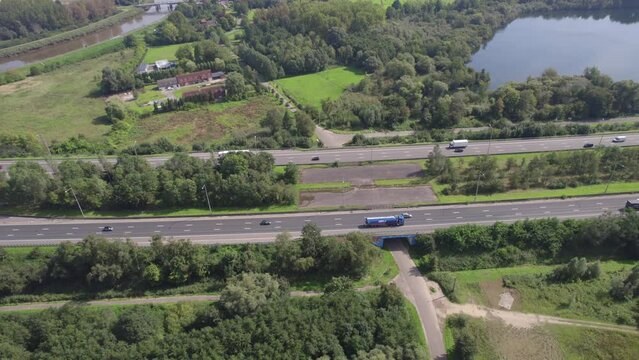 Captured from above in Mechelen, this drone footage showcases the busy E19 highway as it cuts through a vibrant landscape, linking Brussels and Antwerp. The aerial view emphasizes the flow of traffic