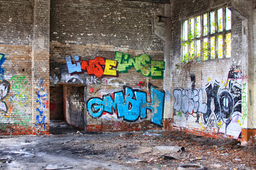 Corner of an abandoned factory hall with graffiti and waste