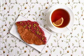 flat croissant with tea and lemon. top view