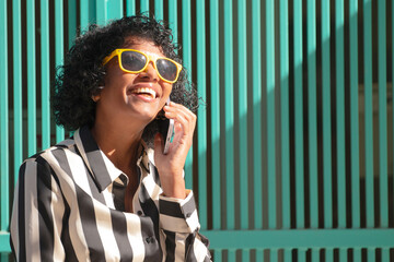 woman smiling on the street with sunglasses talking on mobile phone