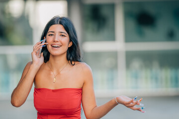 smiling girl in summer clothes on the street talking on the mobile phone