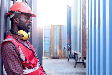 Portrait of African young engineer worker man wears safety red color vest and helmet, feels tired...
