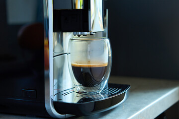 Fresh espresso at morning. Coffee machine with freshly brewed coffee in glass cup. Kitchen...